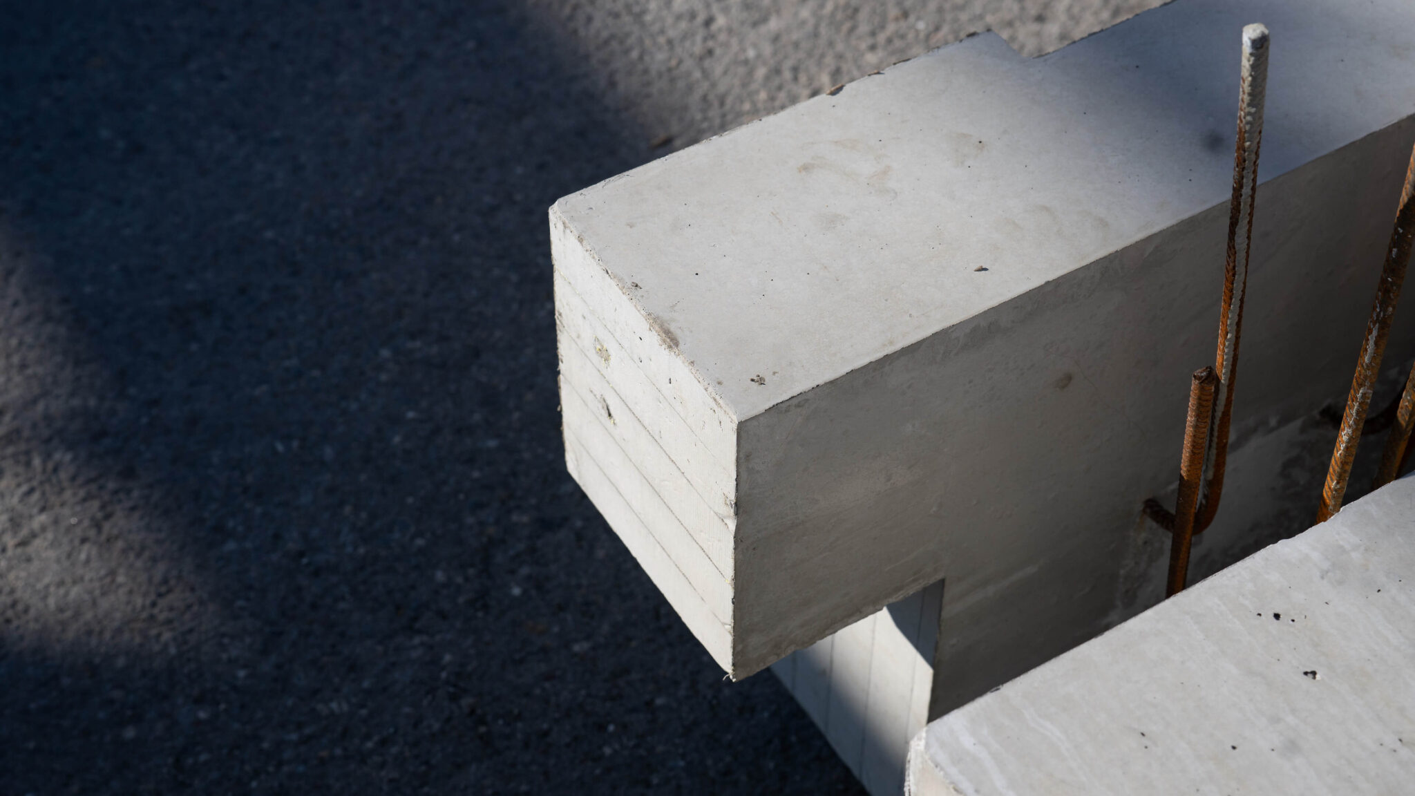 Betonbalken mit herausragenden Stahlarmierungen auf einer Baustelle