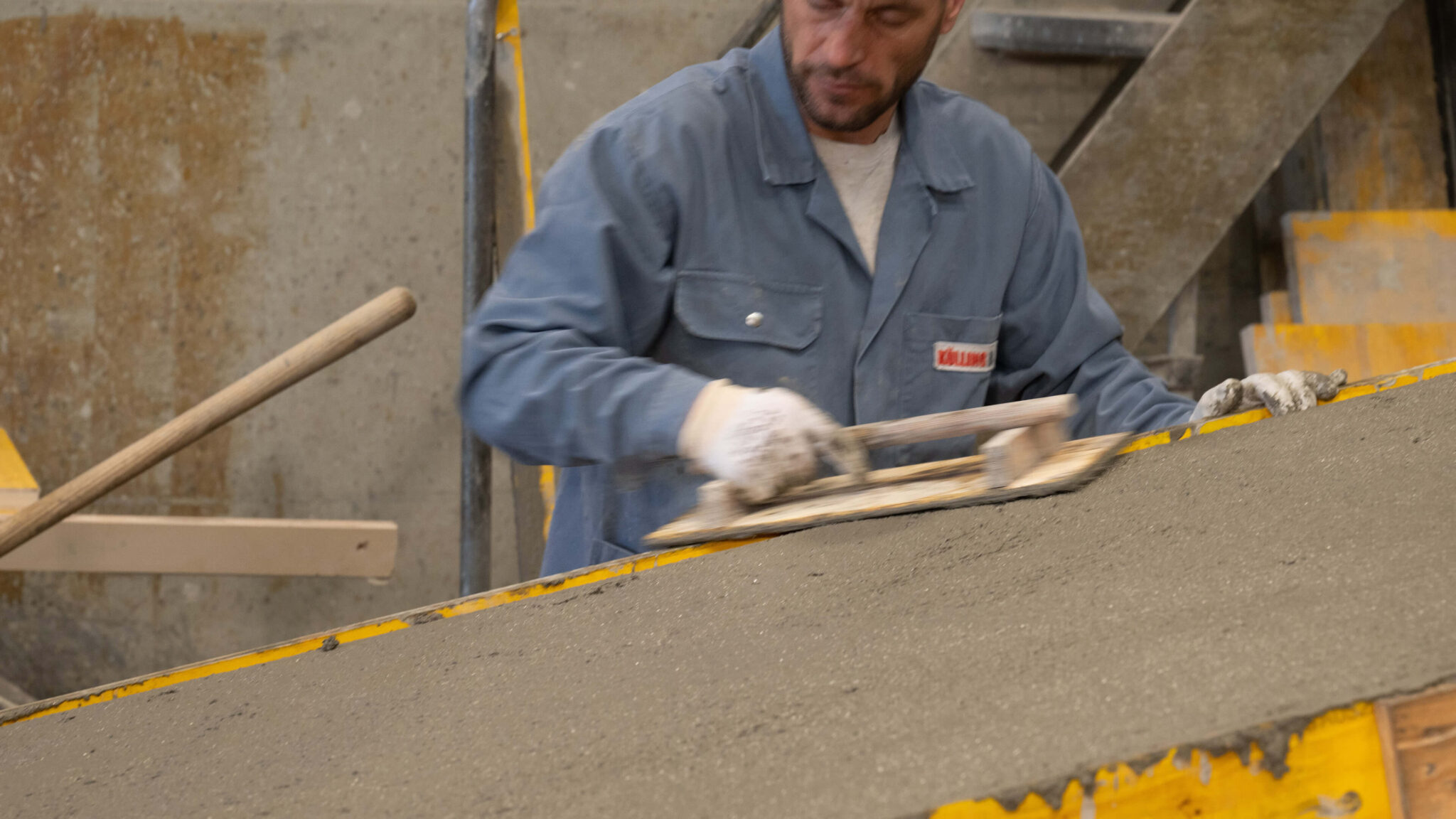 Arbeiter glättet frischen Beton mit einer Kelle in einer Schalung