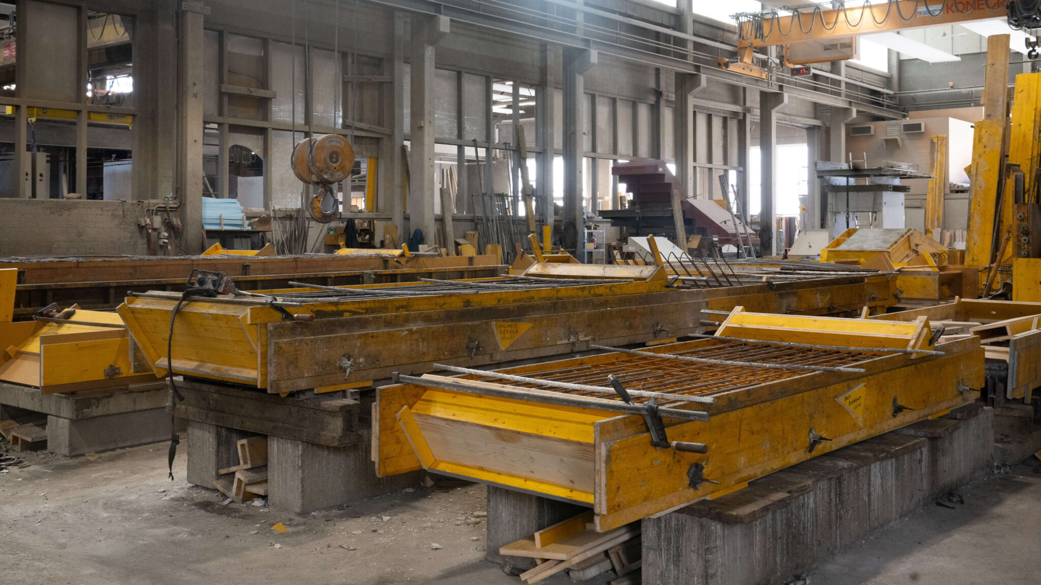 Betonfertigteilwerk mit gelben Schalungen und Stahlbewehrung in einer Produktionshalle