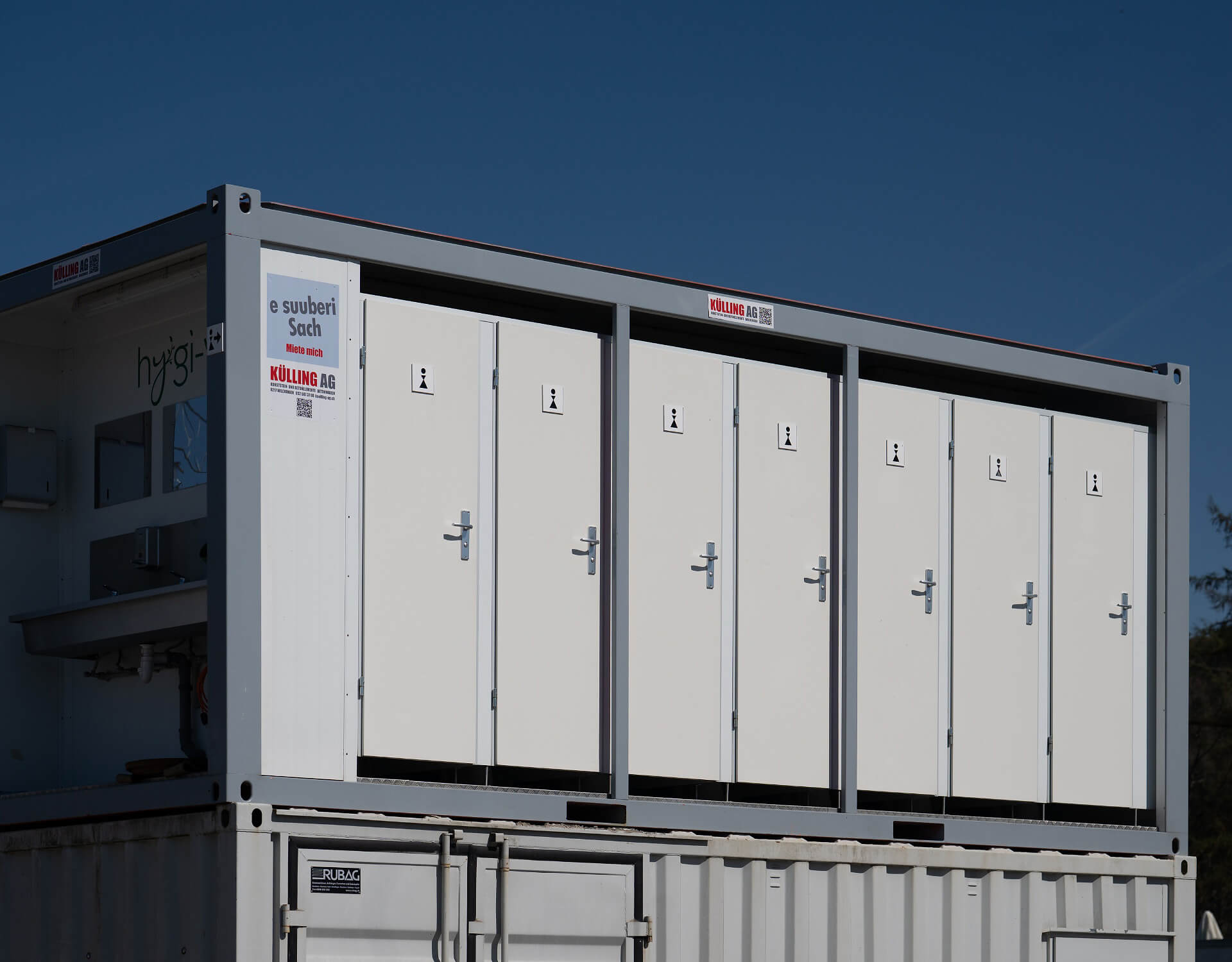 Sanitärcontainer mit mehreren weißen Türen und Beschilderung von KÜLLING AG