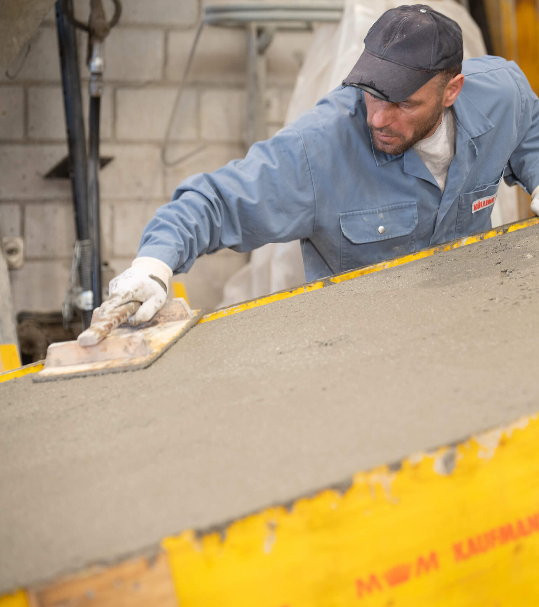 Arbeiter glättet frischen Beton mit einer Kelle