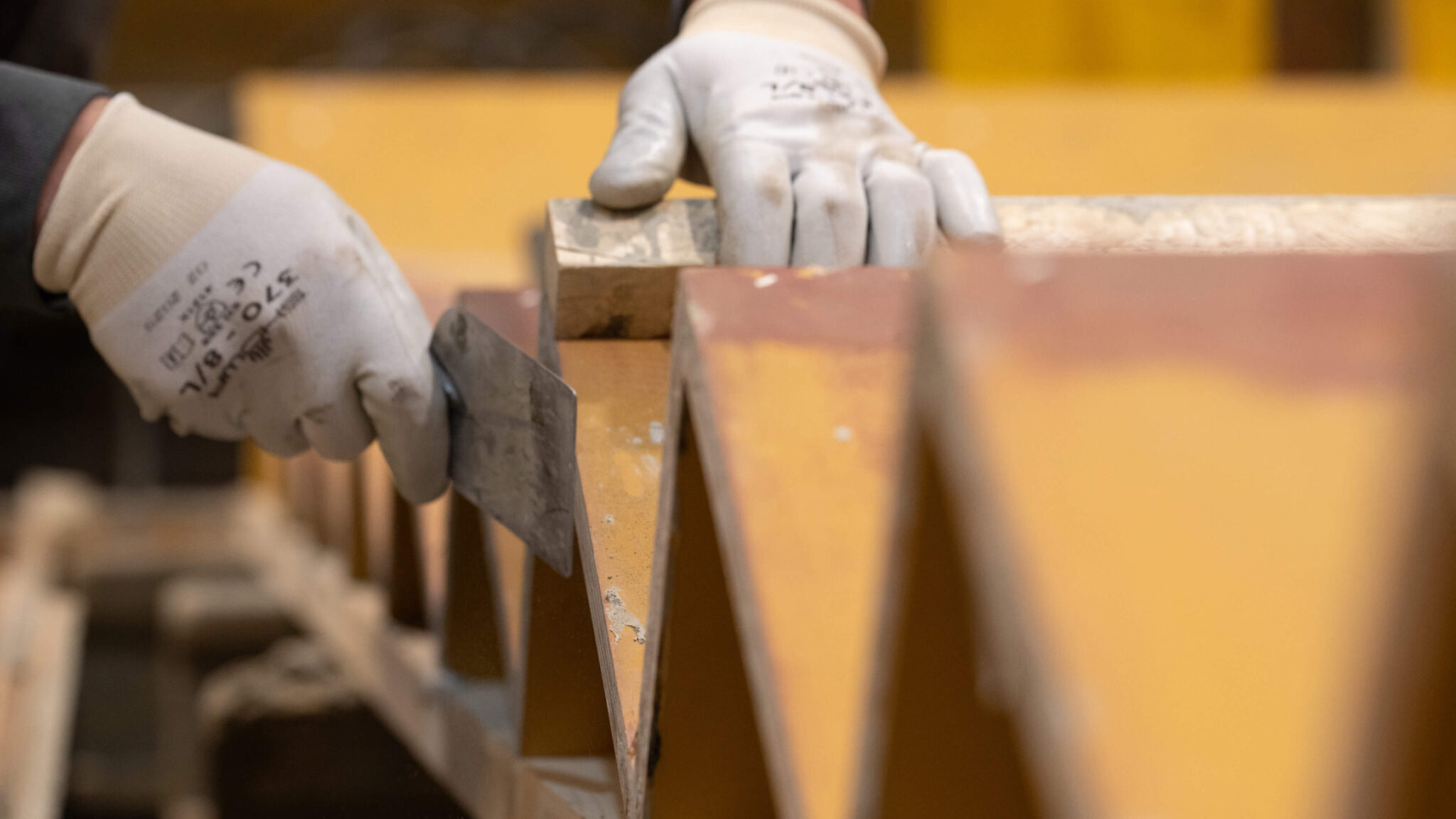 Arbeiter mit Schutzhandschuhen tragen Metallplatten auf einer Baustelle