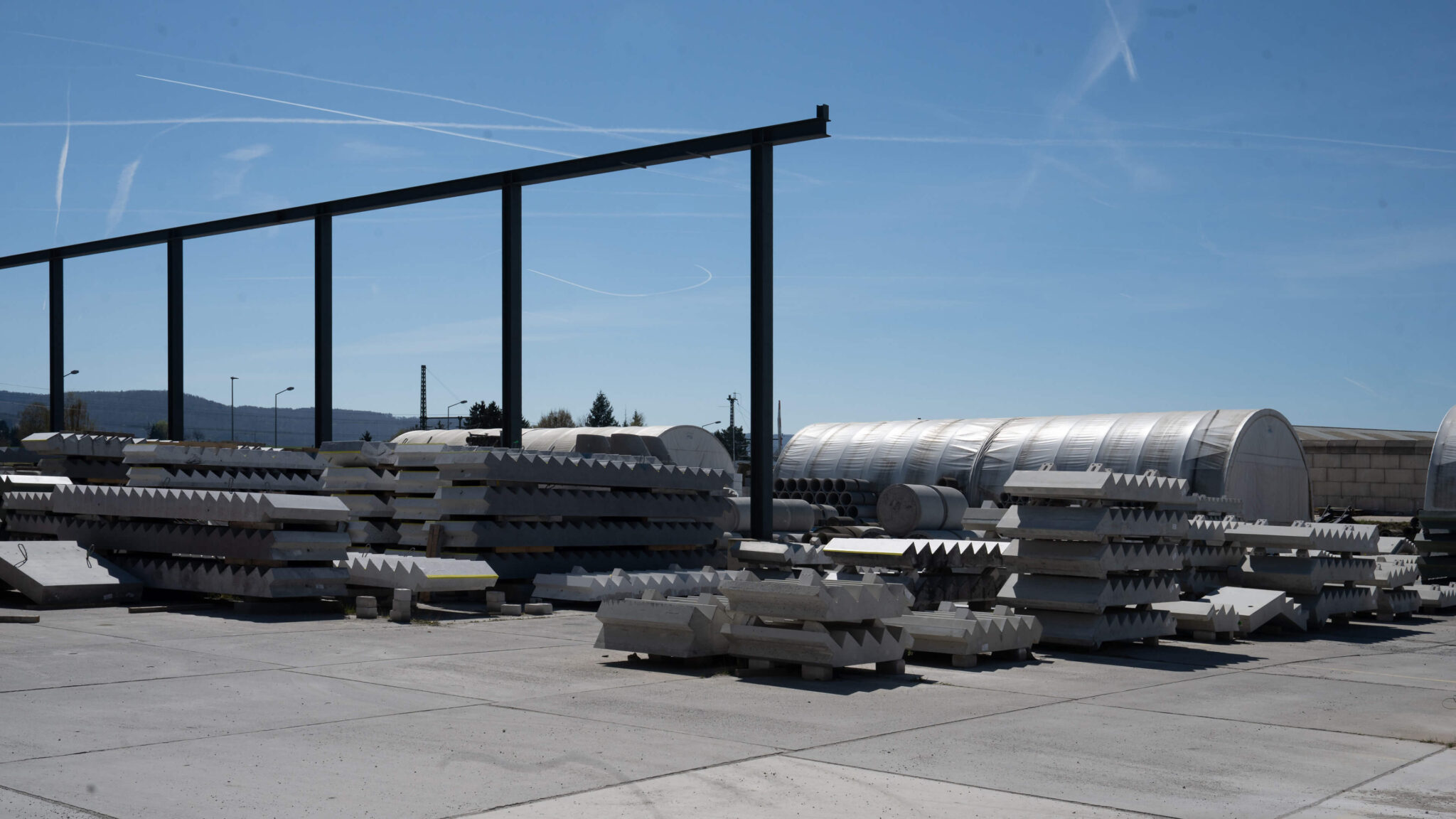 Lagerplatz mit gestapelten Betonfertigteilen unter freiem Himmel
