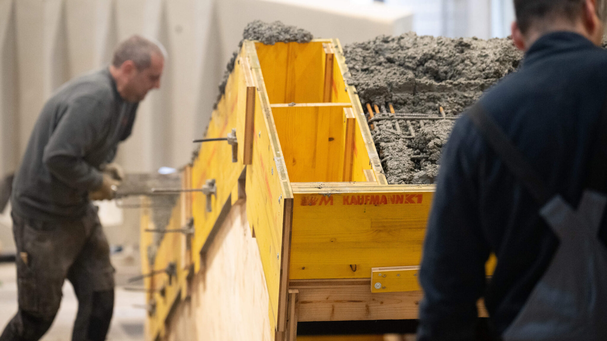 Arbeiter füllen eine Holzschalung mit Beton