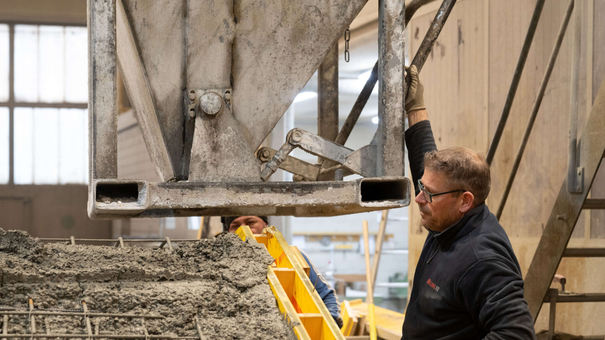 Arbeiter überwacht das Befüllen einer Betonform mit einer großen Maschine