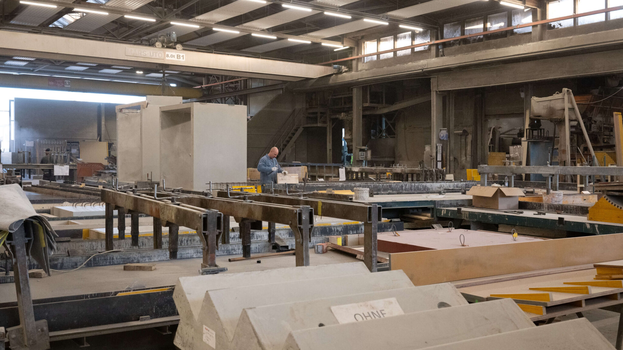 Industriehalle mit großen Maschinen und einem Arbeiter an einer Fertigungsanlage