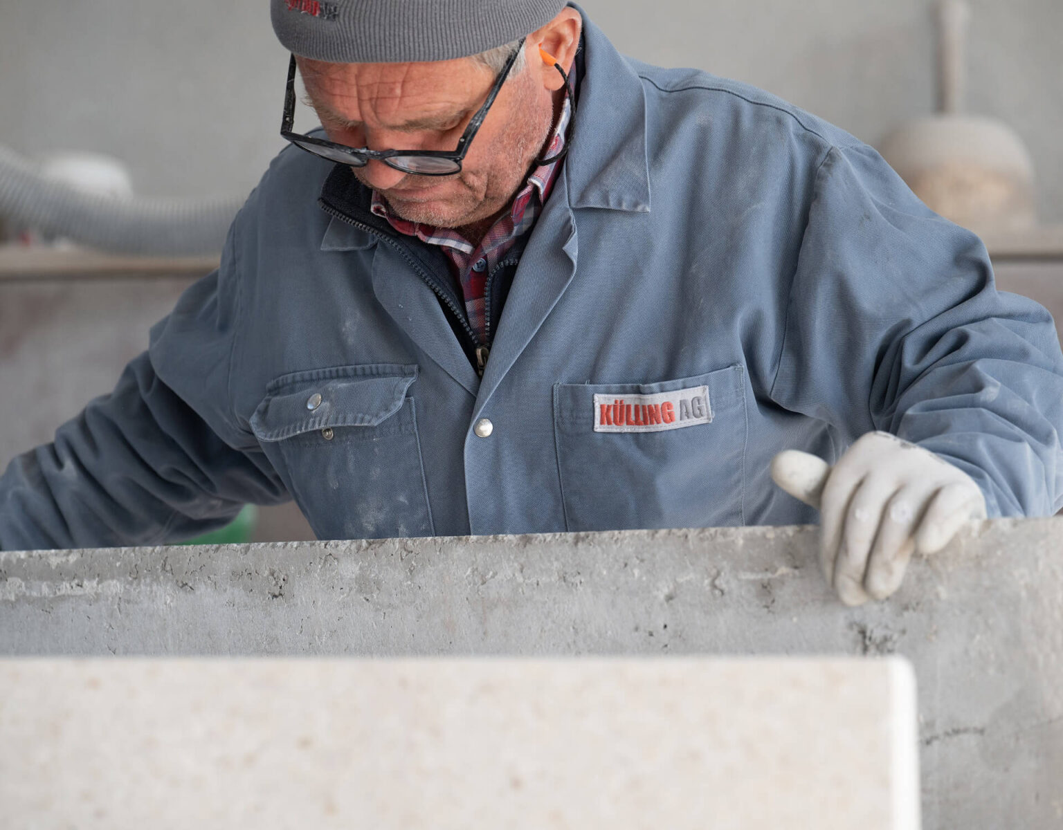 Ein Arbeiter in Schutzkleidung bearbeitet eine Betonplatte