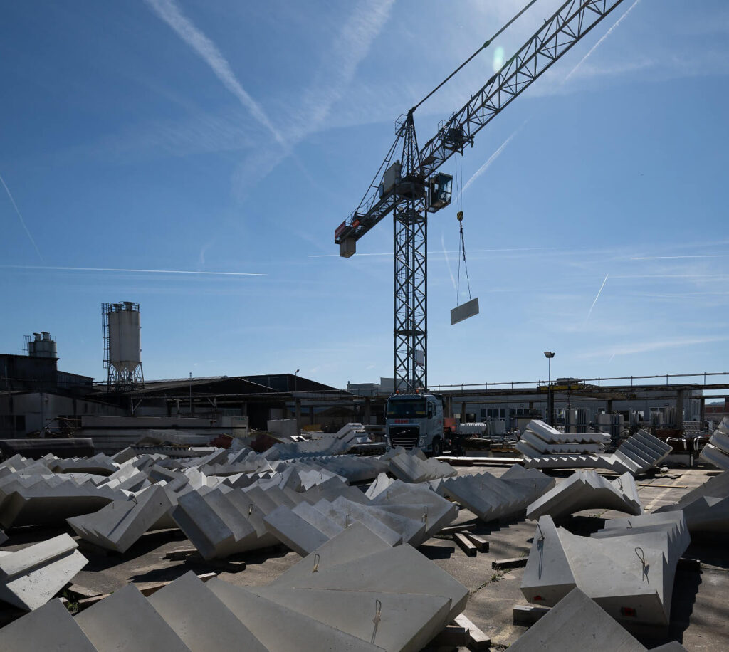 Kran hebt ein Betonelement auf einem Industriegelände