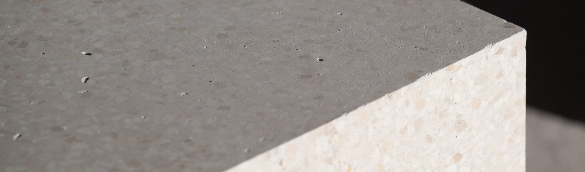 Nahaufnahme einer grauen Betonplatte mit heller Seitenkante