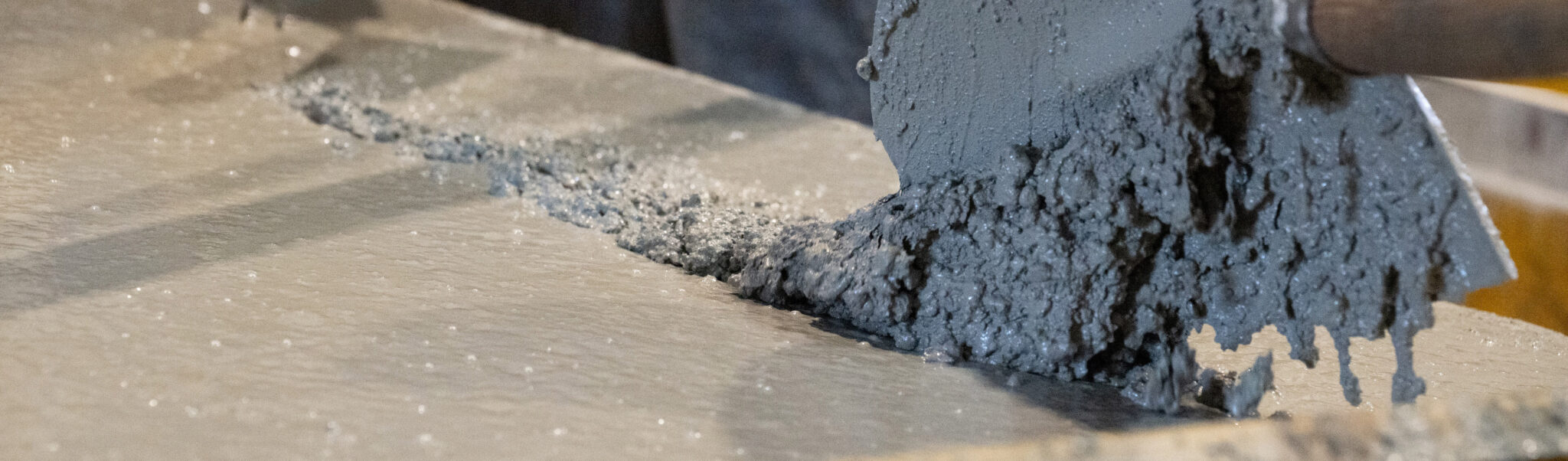 Frischer Beton wird mit einer Kelle auf einer glatten Fläche verteilt