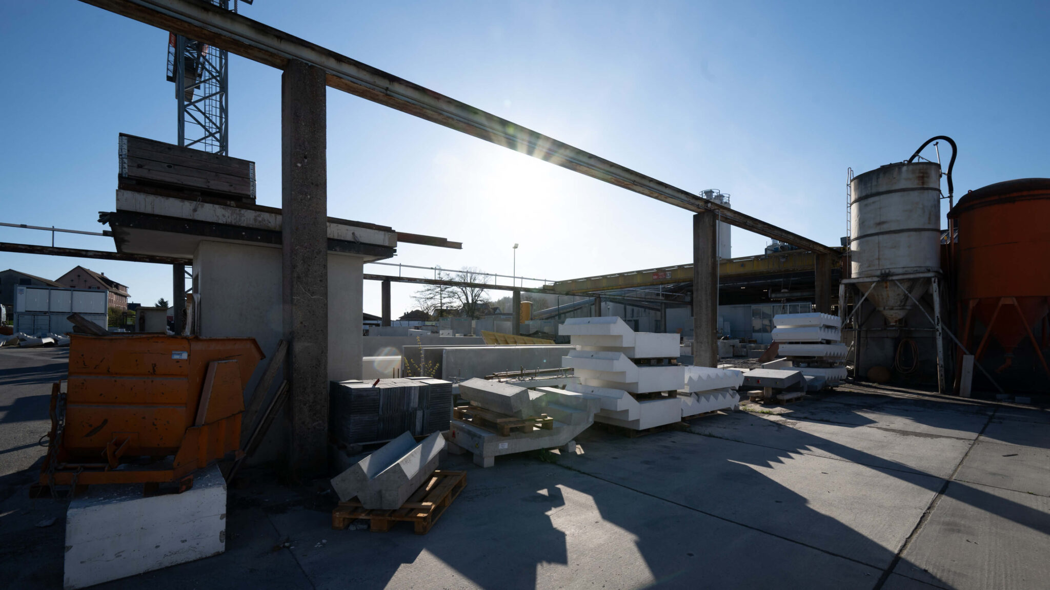 Industriegelände mit gelagerten Baumaterialien und Silos im Sonnenlicht